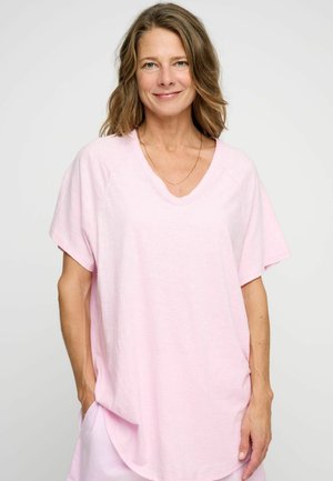 Light pink, loose-fitting t-shirt with a V-neck and short sleeves. Soft fabric with a relaxed design, featuring side pockets.