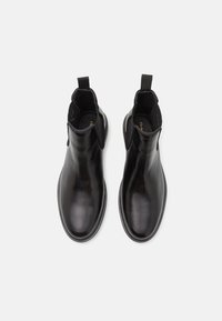 Pair of black leather ankle boots with elastic sides and pull tabs, viewed from above on a white background.