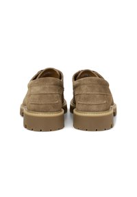 Braune Wildlederschuhe mit runder Zehenpartie und gepolsterten Sohlen, die sich durch auffällige Nähte und ein strukturiertes Rückenteil auszeichnen.