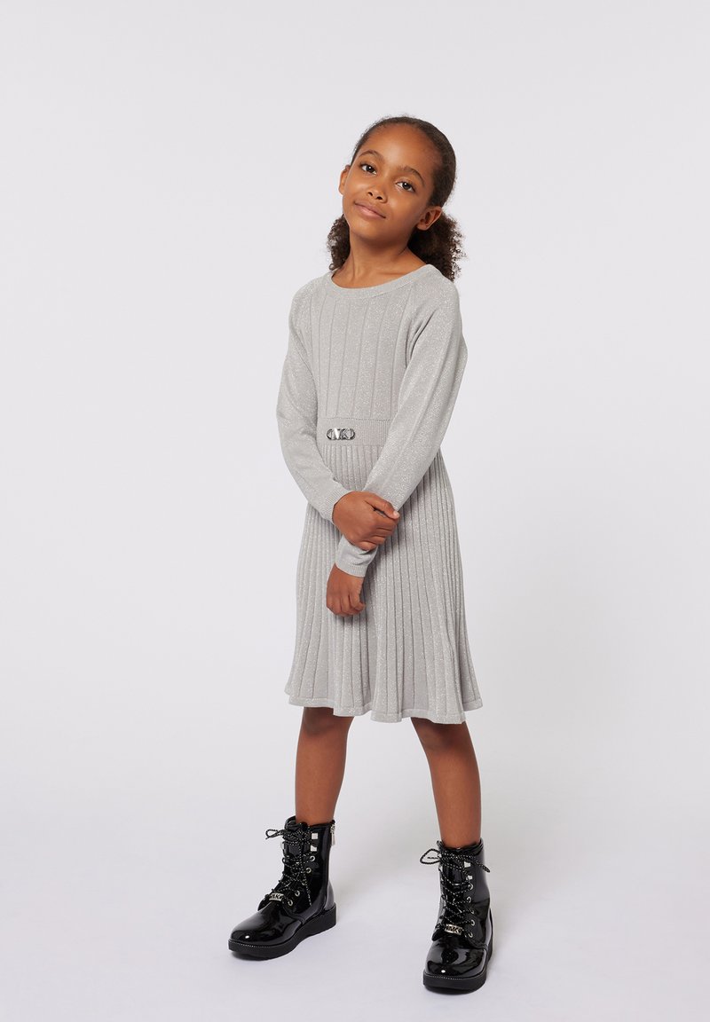 Robe grise côtelée avec des manches longues et un détail de ceinture ; assortie à des bottes en cuir verni noir avec lacets et une semelle épaisse.