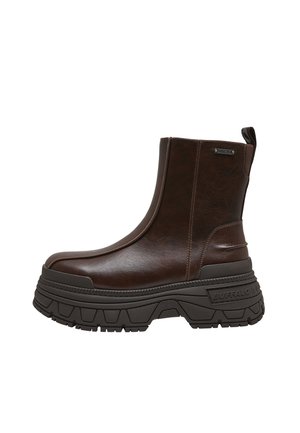 Stivaletto basso in pelle marrone scuro con suola nera spessa e robusta, linguetta posteriore e etichetta con marchio sul lato.