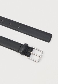 Fekete bőrbőröv sima felülettel, ezüst csattal és több állítható lyukkal. A végek lekerekítettek.