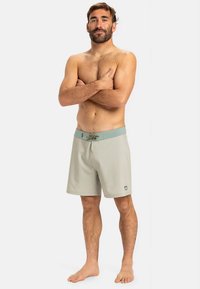 Světle šedé plavky s jednoduchým designem, s tyrkysovým pasem a nastavitelným šňůrkovým zavazováním. Bez vzorů nebo viditelných kovových prvků.