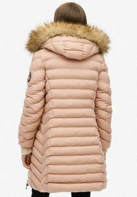 Giacca imbottita rosa con cappuccio in pelliccia sintetica. Presenta cuciture orizzontali, polsini a coste e zip laterali per la ventilazione.