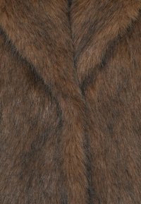 Bruine nepbontstof met een zachte, gestructureerde oppervlakte en prominente variaties in kleur en dikte, wat een natuurlijke uitstraling creëert.
