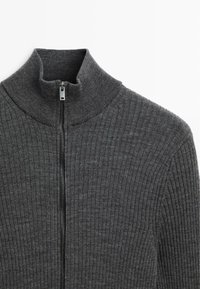 Grauer gerippter Pullover mit hohem Kragen und Frontreißverschluss, aus strukturiertem Stoff für Wärme und eine enge Passform.