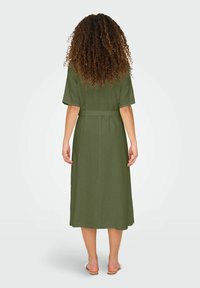 Olive green, mid-length dress with short sleeves, a belted waist, and a straight silhouette; fabric appears textured.