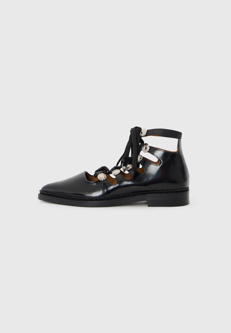 Schwarzer Lackleder-Stiefelette mit Ausschnitten, Schnürdesign und dekorativen Metallakzenten. Abgerundete Spitze und niedriger, robuster Absatz.