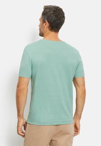 Mintgroene T-shirt met korte mouwen, zachte textuur, ronde hals, ontspannen pasvorm. Licht materiaal met subtiele kleurvariaties. Geen zichtbare logo's.