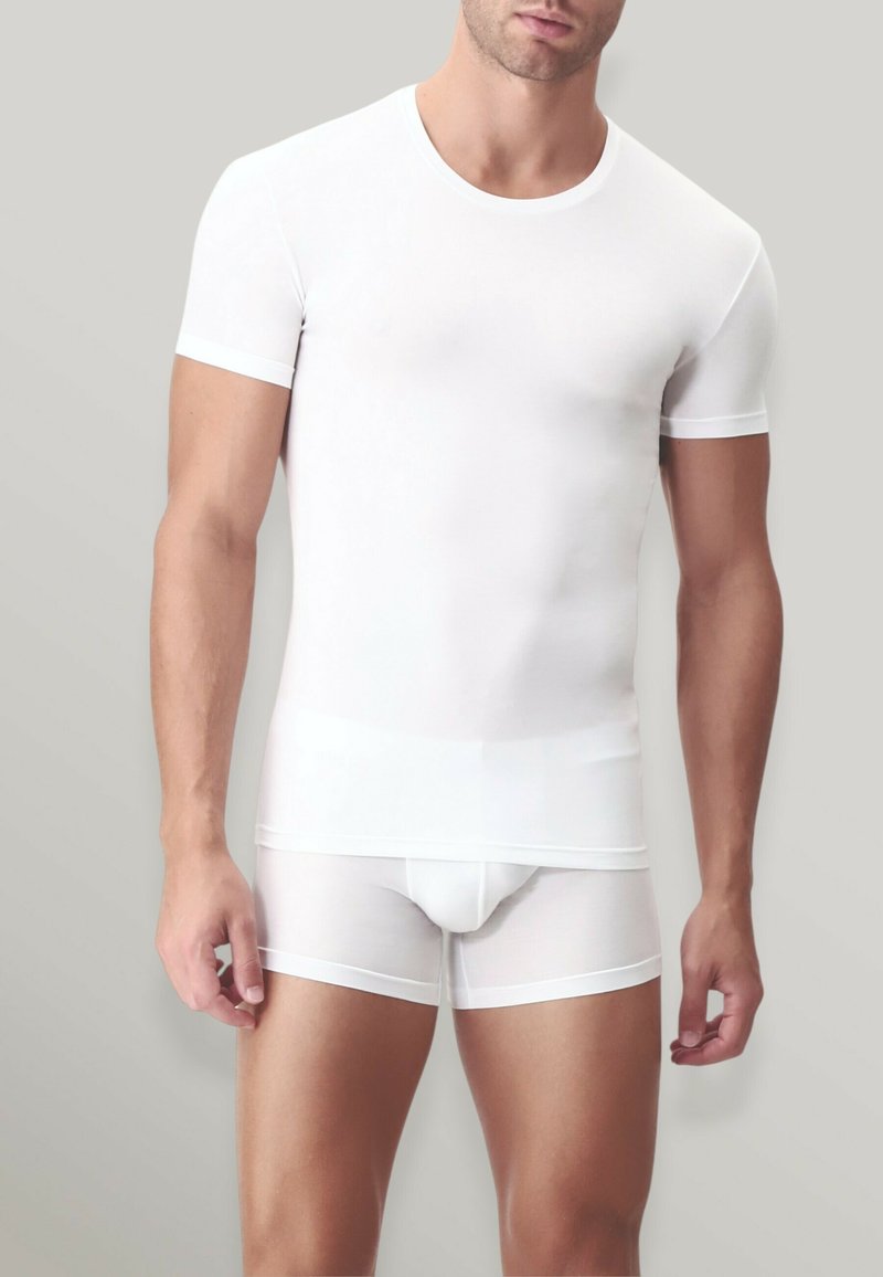 T-shirt bianco aderente a maniche corte e boxer realizzati in tessuto morbido con dettagli in contrasto sulle bordure. Morbido, elastico e leggero.