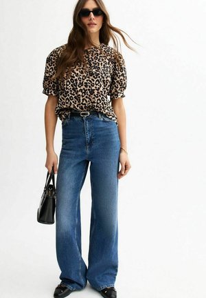 Blouse met luipaardprint en korte mouwen, hoge taille met wijde blauwe jeans en zwarte handtas. Glad materiaal en een losse fit. Zwarte zonnebril.