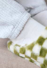 Green and white checkered fleece slippers with a texture, featuring a white ribbed ankle sock and a small label marked "NEXT."