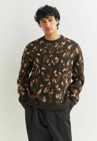 Sweter dzianinowy w ciemnym brązie z wzorem w panterkę w beżu i jasnym brązie. Okrągły dekolt oraz ribbowe mankiety i dół.