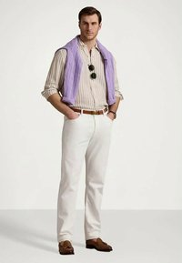 Šviesiai violetinis megztinis su pynėmis, užmestas ant dryžuoto marškinių su sagomis, derinamas su baltomis kelnėmis ir rudais loafers batais. Akiniai nuo saulės ant marškinių.