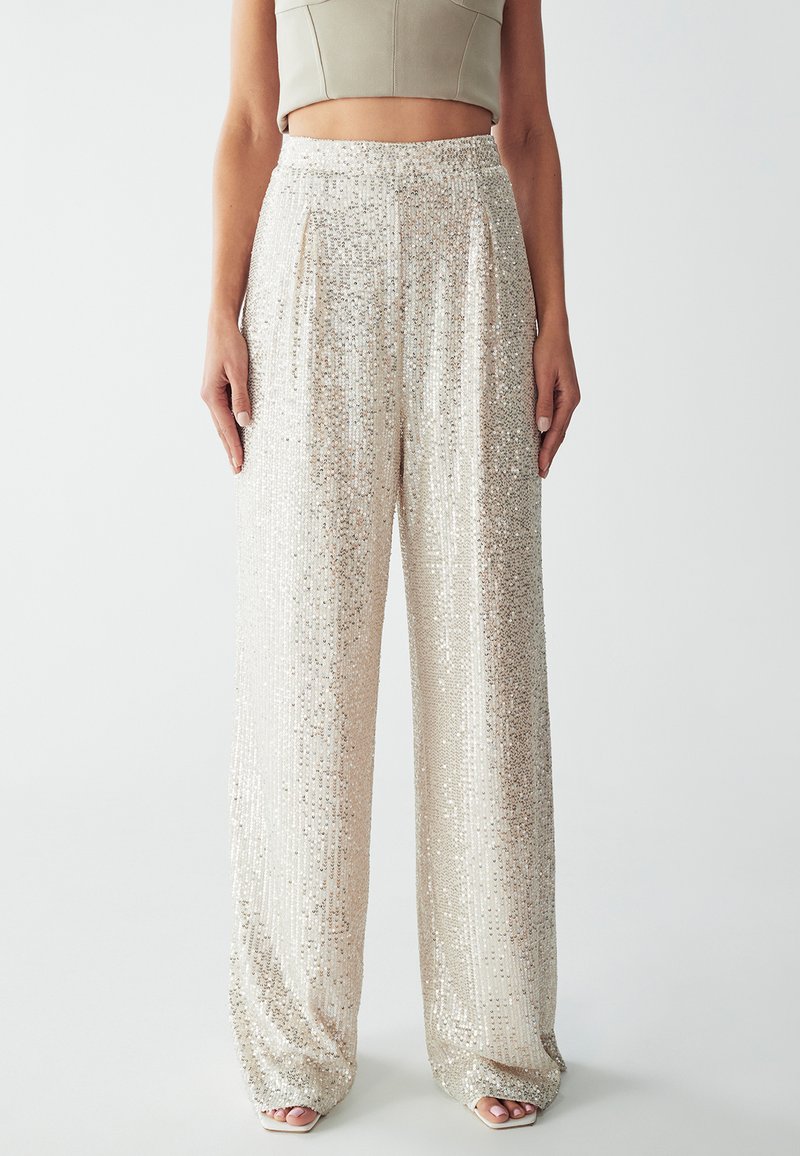 Pantaloni larghi in paillettes con una sfumatura di oro e argento, caratterizzati da una superficie testurizzata e una vita elasticizzata. Finitura in tessuto liscia.