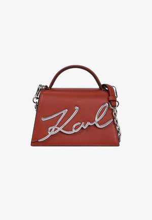 Punane nahast käekott, millel on struktureeritud kuju, hõbedane "Karl" logo, kahekordne käepide ja eemaldatav kett.
