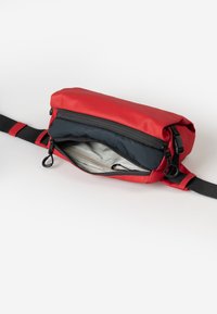 Rode heuptas met een zwart verstelbaar band, gedeeltelijk open hoofdrits die de lichtgrijze voering en een klein ritsvakje binnenin onthult.