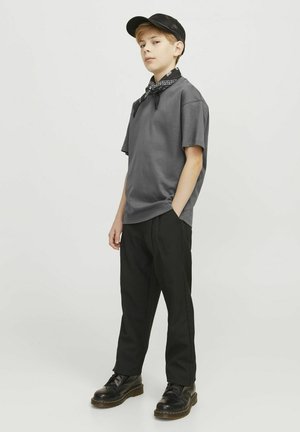 Grå bomulds t-shirt i afslappet pasform, parret med sorte bukser. Accessories inkluderer en sort cap og et sort bandana bundet om halsen.