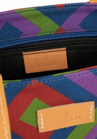 Borsa in tela con vivaci motivi geometrici in viola, verde, rosso e blu. Presenta un'etichetta in pelle con la scritta "GALLO" in rilievo e una chiusura con zip.