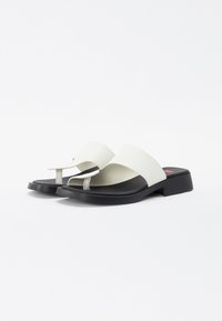 Vita läder flip-flop sandaler med en svart gummisula, med en tvådelad överdel och en liten tårem, slät textur.