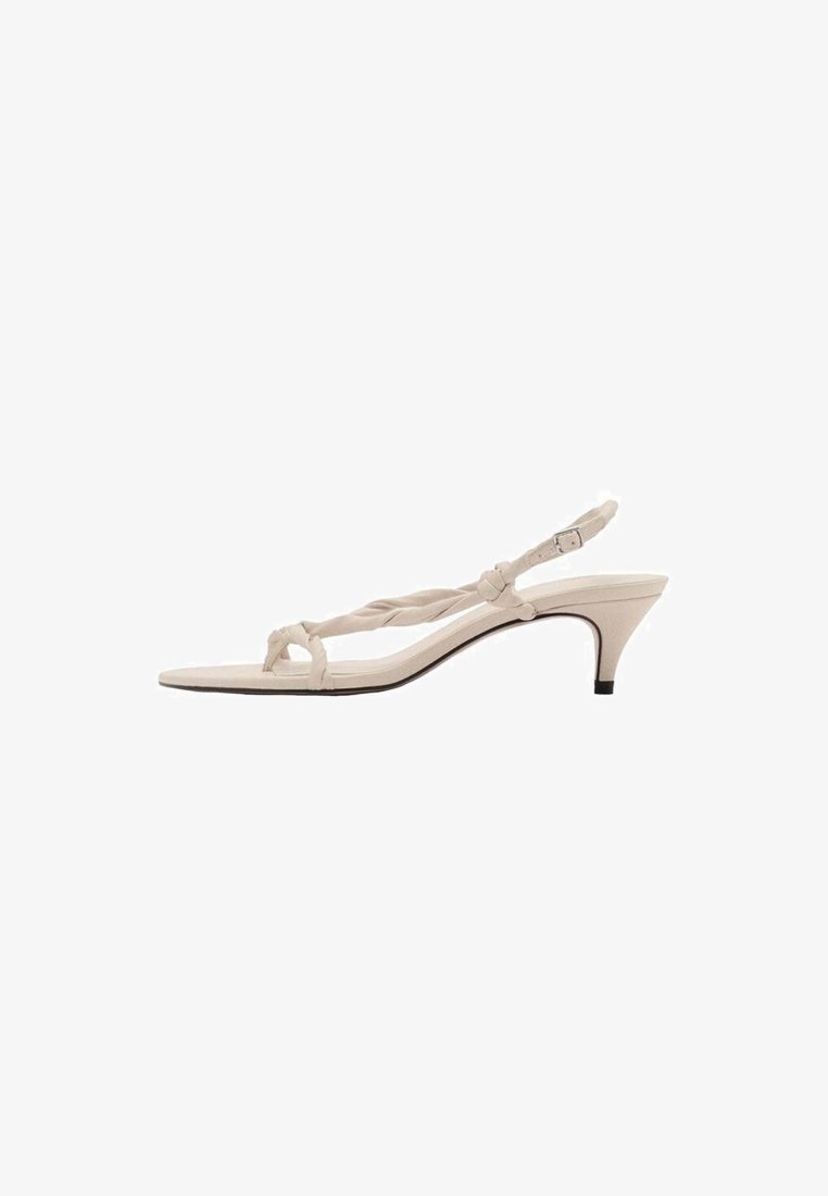 Beige slingback sandal med flätad remdesign, spetsig tå och låg klack. Slät textur med en minimalistisk look.