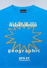 Bright blue t-shirt featuring a yellow zigzag design and bold white text: "NAPAPIJRI geographic" and "GPS-ET MAPPING SURVEYS."