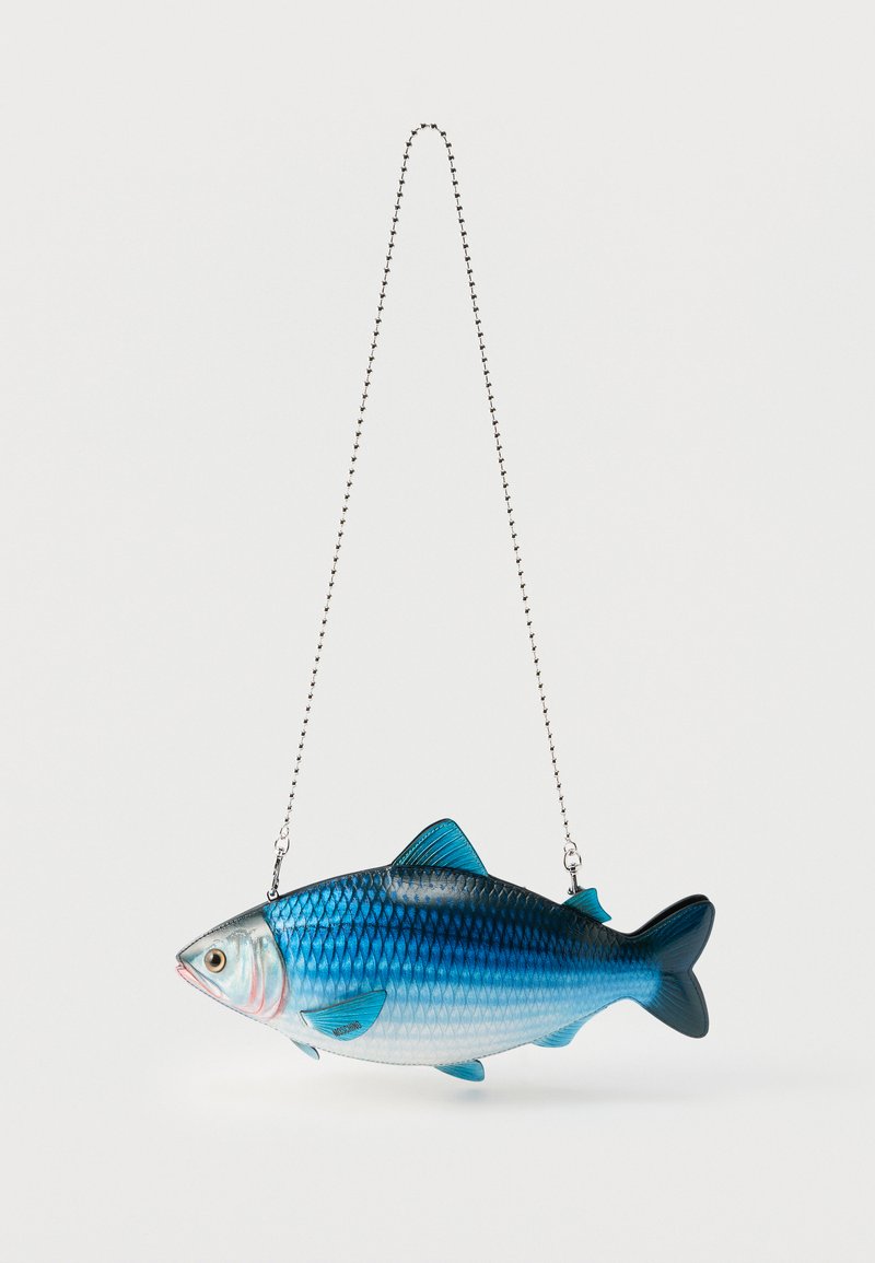 Τσάντα σε σχήμα ψαριού σε μπλε και ασημί χρώμα, με λεπτομερείς λέπια, πτερύγια και μάτια, κρεμασμένη από λεπτή ασημένια αλυσίδα σε λευκό φόντο.