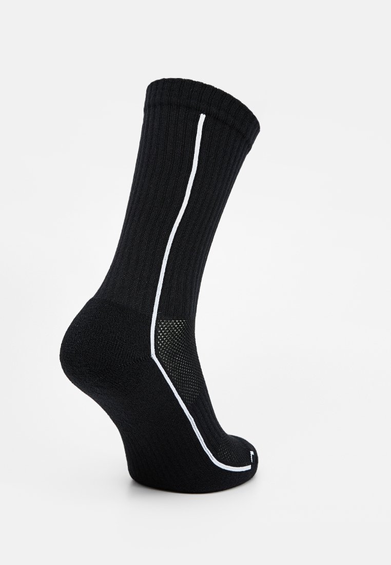 Calcetín negro acanalado que presenta una franja vertical blanca, sección del pie texturizada y un talón reforzado. El material parece cómodo y elástico.