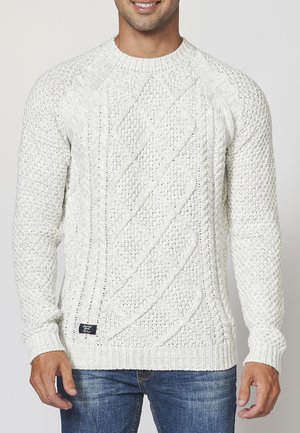 Jersey de color crema tricotado con patrones de trenzado, escote redondo y puños y dobladillo de canalé. Hilo texturizado, corte estructurado, estilo casual.