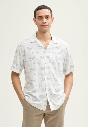 Chemise à manches courtes avec boutons en tissu léger, fond blanc, ornée d'un motif subtil de palmiers en noir et dans des teintes claires.