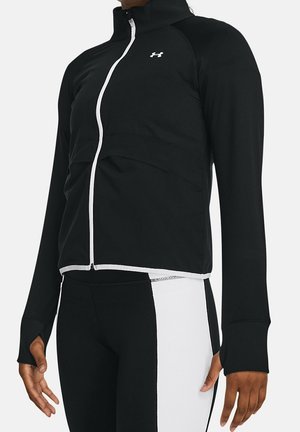 Veste de sport noire avec col montant, fermeture éclair sur le devant et accents blancs. Présente des manches longues avec trous pour le pouce et une coupe ajustée.