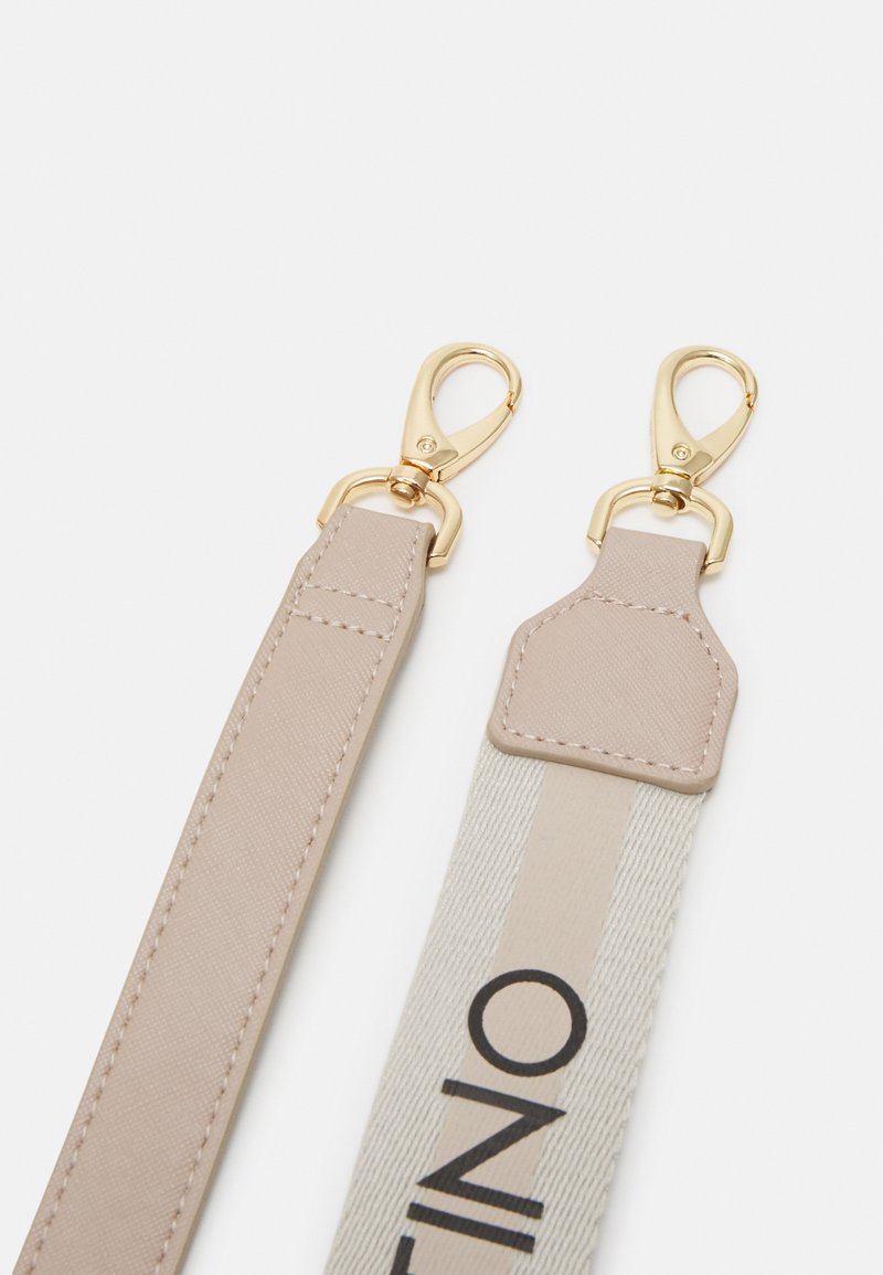 Sangle beige en tissu et cuir avec des éléments en métal doré. Présente une face à motifs avec un logo et une face lisse, sans embellissement.