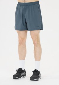 Mäns atletiska shorts, blågrå, lätt material, elastisk midja, sidoklyftor, "ENDURANCE"-logotyp på nedre vänstra benet. Matchas med svarta skor.