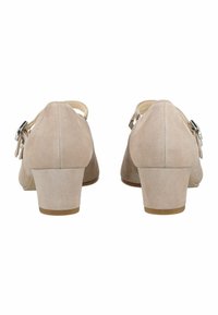 Beige suède schoenen met hak, een afgeronde neus, enkelriem en een klein metalen gespje. De hakken zijn ongeveer 5 centimeter hoog.