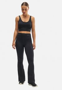 Top corto atlético negro y leggings acampanados hechos de material elástico. El diseño cuenta con una cintura alta y sutiles detalles de logo.