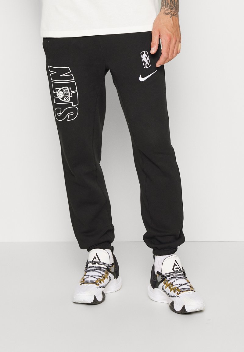 Svarta sweatpants med en avslappnad passform, med en vit "Nets"-logo och Nike swoosh. Cuffade anklar, tillverkade av mjukt tyg; avslappnad design.