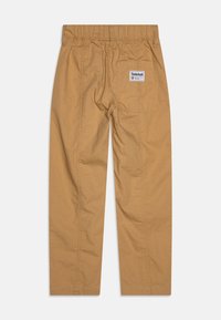Smeđe pamučne hlače s elastičnom trakom, ravnim nogavicama i jednom stražnjom džepom s Timberland oznakom. Teksturirani, izdržljiv materijal.