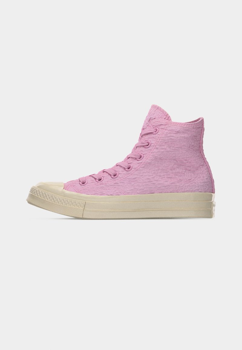 Sneaker alta in tessuto rosa increspato con suola e punta in gomma beige, vista laterale su sfondo grigio chiaro uniforme.