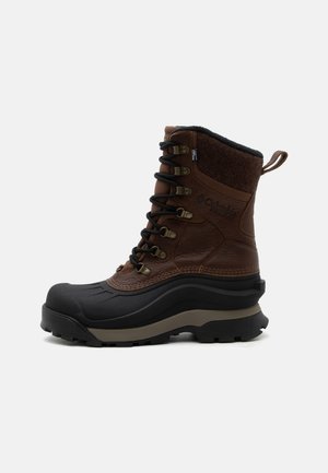 Botte d'hiver isolée marron et noire avec tige haute, semelle épaisse, œillets métalliques et col matelassé pour protection contre le froid.