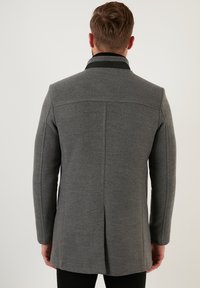 Grå uldblandingsfrakke med struktureret design, lange ærmer, høj krave og slids bagpå.