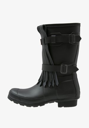 Czarna gumowa botka sięgająca do połowy łydki z paskami z klamrami i warstwowym frędzlem po boku, wyposażona w wytrzymałą podeszwę i zaokrąglony nosek.