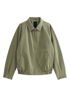 Veste légère vert olive avec col montant, fermeture à glissière, poches latérales et ourlet élastiqué. Tissu lisse à finition mate.