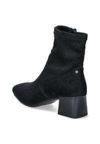 Bottine noire avec un bout pointu, fabriquée en daim doux. Elle possède un petit talon carré et une fermeture éclair sur le côté. Texture lisse.