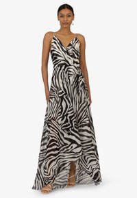 Maxikleid aus transparentem Stoff, mit einem schwarz-weißen Zebramuster, Wickeldesign und verstellbaren Spaghettiträgern. Hohe Schlitzdetails.