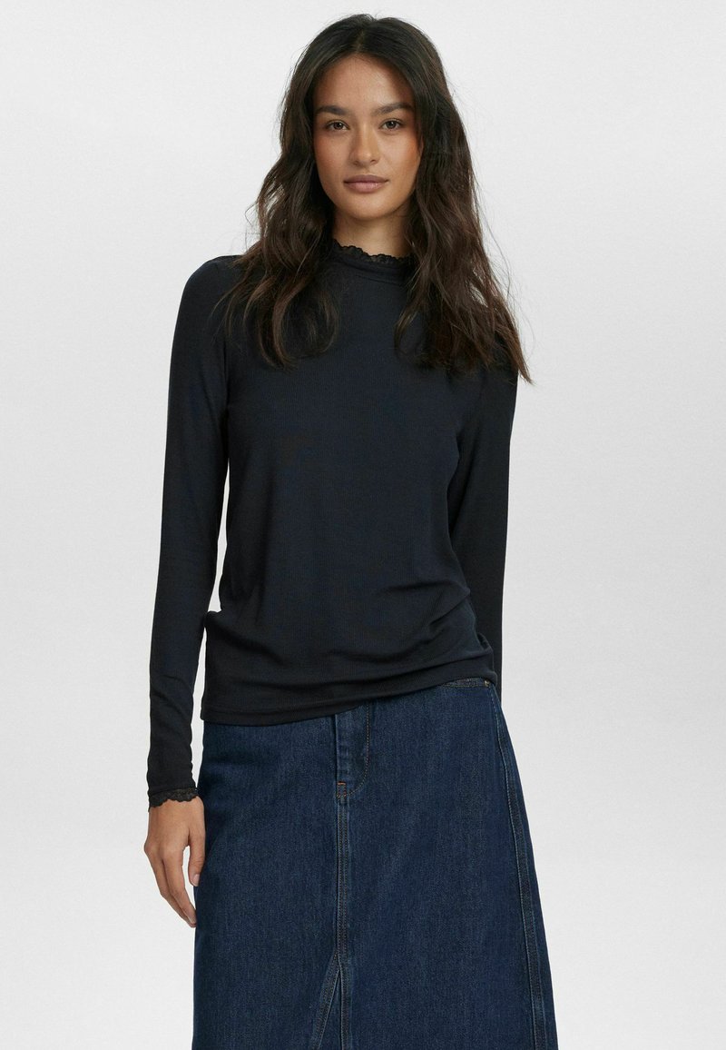 Svart långärmad topp med ribbad textur och scallopkrage, matchad med en denimkjol med en framklippt slits.