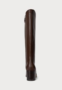 Bota de cuero marrón hasta la rodilla con punta redondeada, tacón bloque y detalle de cremallera lateral. Textura suave, acentos de costura mínima.