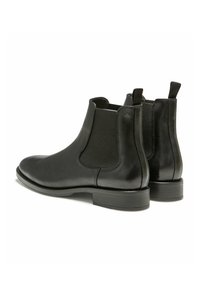 Bottines Chelsea en cuir noir avec des panneaux élastiques sur les côtés, des orteils arrondis et des tirettes. Texture lisse avec un talon empilé.