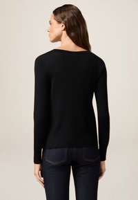 Schwarzer Strickpullover mit rundem Ausschnitt, langen Ärmeln und entspannter Passform. Von hinten dargestellt, zeigt er eine glatte Textur und Saumlinie.