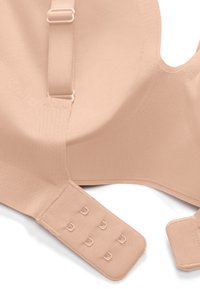 Reggiseno beige senza cuciture con spalline regolabili e chiusura a tre file di ganci, progettato per comfort e vestibilità uniforme.