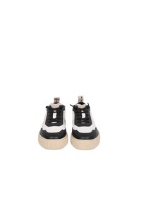 Baskets blanches et noires avec des semelles en caoutchouc texturé, un laçage à l'avant et une finition mate lisse sur les accents noirs.